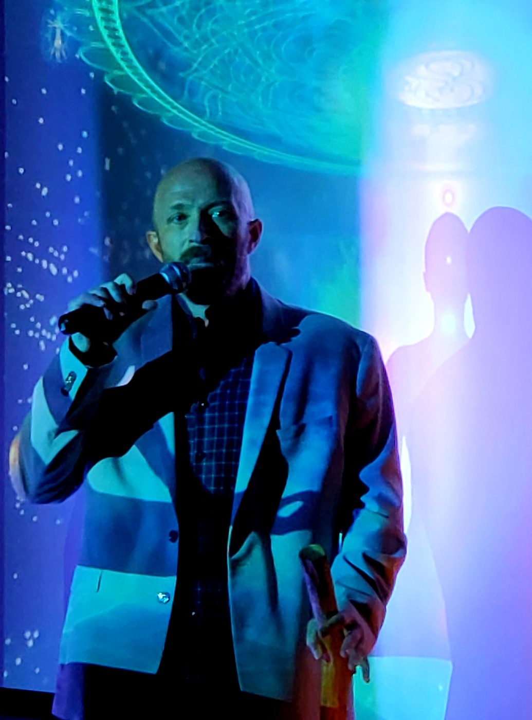 Russ speaking with a microphone on a lit stage
